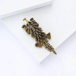 Detailed macro view of vintage bronze pangolin brooch with amber rhinestones on a white block