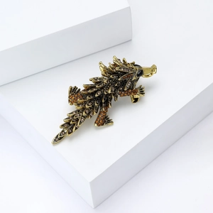 Macro shot of retro gold crocodile brooch with amber rhinestones on a white pedestal
