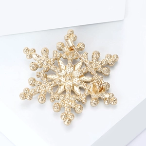 Detailed macro view of the secure golden snowflake brooch pin with rotating safety clasp