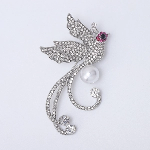 Détail d'une broche phénix de luxe avec strass étincelants et une grande perle