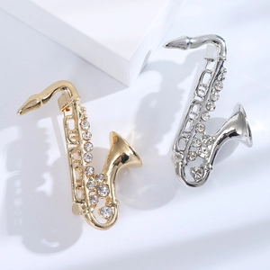 Spille a sassofono eleganti color oro e argento con cristalli su blocchi geometrici bianchi