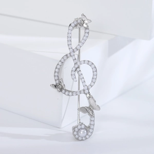 Detailed shot of treble clef music brooch with white pearls and butterfly accents