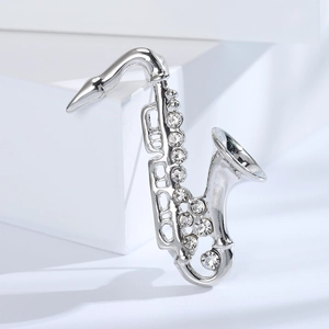 Dettaglio spilla a forma di sassofono argento con strass su supporto bianco