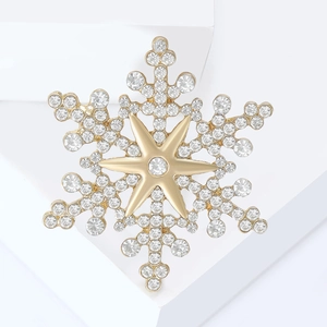 Close-up of golden snowflake brooch with sparkling crystals on white geometric stand