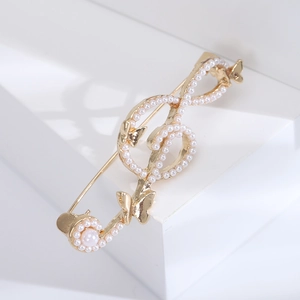 Elegant gold musical note brooch with pearls and butterflies on white geometric display
