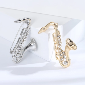 Dettaglio ravvicinato delle spille a forma di sassofono con cristalli in oro e argento