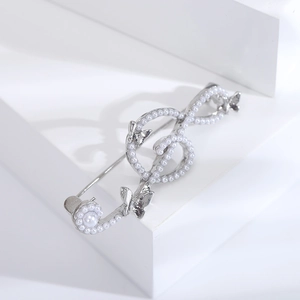 Detailed macro shot of silver tone treble clef brooch with white faux pearls and butterfly