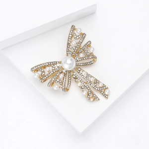 Macro shot of elegant bow brooch with white pearls and micro-pave crystals in gold finish