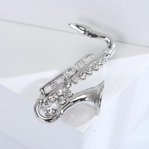 Elegante spilla a forma di sassofono argento con strass lucidi su un piedistallo bianco