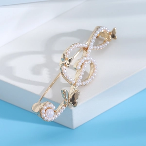 Detail of a gold treble clef brooch with white pearls and butterfly accents on blue background