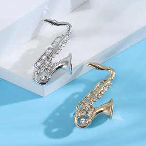 Dettaglio delle spille a forma di sassofono in oro e argento con strass di cristallo lucidi