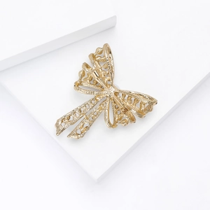 Macro shot of gold bow brooch featuring intricate hollow design and textured finish