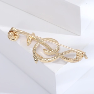 Detailed back view of golden music note brooch with small white pearls and long pin clasp