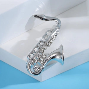 Dettaglio macro della spilla a sassofono in argento con strass lucidi e design musicale