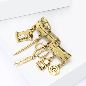 Close-up of vintage gold sewing brooches featuring scissors, thread, and thimble charms