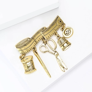 Detail of vintage sewing theme brooch with gold measuring tape and tool charms
