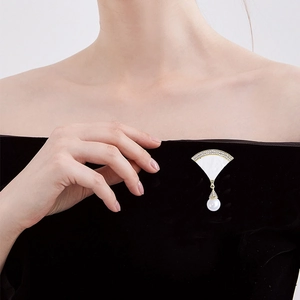 Eleganter fächerförmiger Muschel-Brosche mit Strass und Perle auf schwarzem Samtkleid