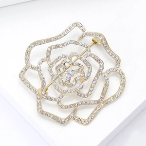 Détail macro d'une broche camélia dorée ajourée avec strass scintillants et cœur en cristal