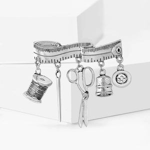 Vintage silver sewing tool brooch with scissors, thread spool, and needle charms