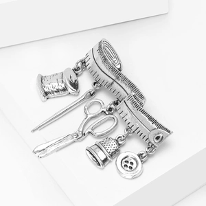 Close-up of vintage sewing tool brooch with scissors, thimble, and spool charms