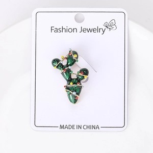 Detailed close-up of a green cactus brooch with colorful enamel dots on white cardstock