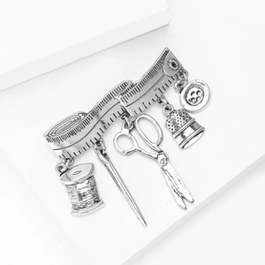 Detail of vintage silver sewing charm brooch with miniature scissors and thread spool