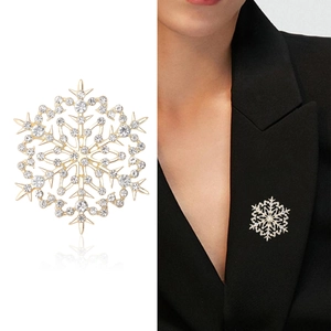 Élégante broche flocon de neige dorée avec cristaux sur blazer noir et fond blanc