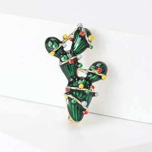 Detail of green enamel cactus brooch with colorful beads on white geometric base