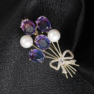 Vue macro d'une broche bouquet avec cristaux violets et perles sur fond en cuir noir