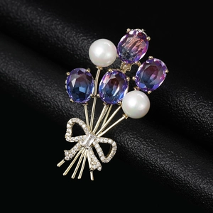 Vue macro d'une broche ballon en pierres violettes avec perles et nœud doré élégant