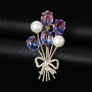 Détail d'une broche ballon dorée avec pierres violettes et nœud en diamant sur cuir noir