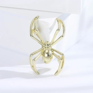 Polished gold spider brooch for men's suits displayed on a white geometric stone block