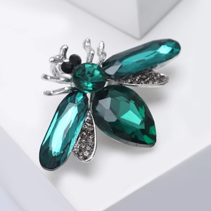 Detail of emerald crystal bee brooch featuring silver metal legs and rhinestone wings