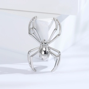 Detailed view of a polished silver spider brooch with a mirror-like metallic finish