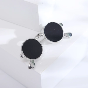 Detailed close-up of a silver sunglass brooch with black lenses and rhinestone accents