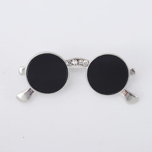 Detailed close-up of a silver sunglasses brooch with black enamel and white rhinestones