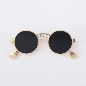Detail view of retro sunglasses brooch with gold frame, black lenses and crystal inlay