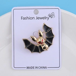 Macro detail of bat-shaped enamel brooch with black wings on a white jewelry card
