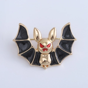 Detailed view of the gold-plated alloy bat brooch with black enamel wings and red eye accents