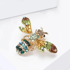 Détail d'une broche abeille avec ailes en émail vert et strass multicolores sur base dorée