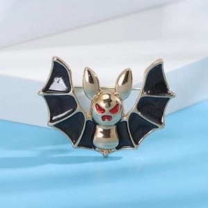Detail of bat-shaped gold metal brooch with black enamel wings and red eye accents