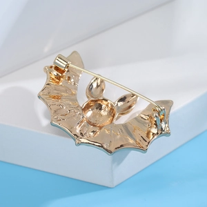 Macro view of golden bat brooch back with pin clasp mechanism on white display stand