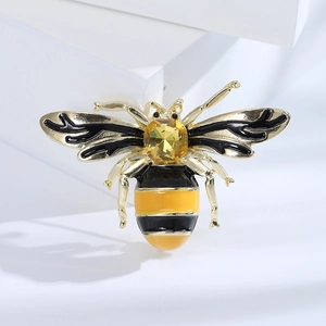 Macro detail of bee brooch with yellow gemstone and colorful enamel on white background