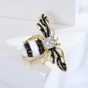 Detailed close-up of a gold bee brooch featuring black enamel and a sparkling crystal gem