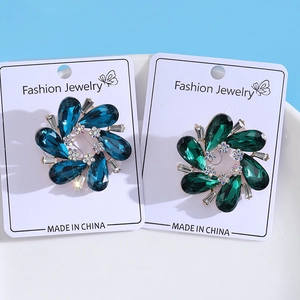 Detail of dark blue and emerald crystal flower brooches on golden metal base