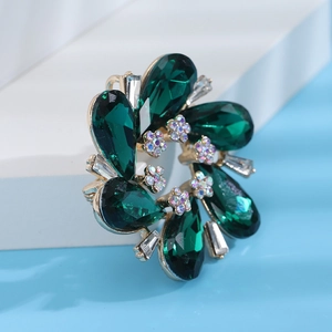 Detailed close-up of a floral brooch with green crystals and small sparkling zircons