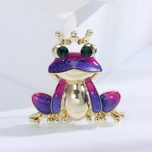 Creative crown frog brooch with purple enamel and green crystal eyes on white background