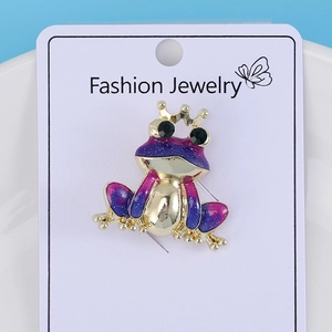 Detailed view of frog enamel brooch with purple gradient and green gemstone eyes