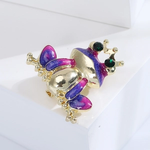 Close-up of cute crown frog brooch with colorful enamel finish and green gemstone eyes
