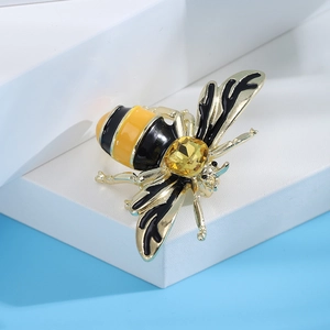 Macro detail of bee brooch with yellow gemstone and enamel wings on a blue base